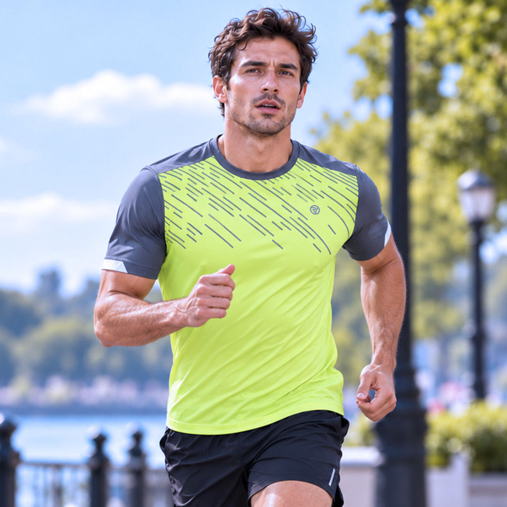 lifestyle A man running outdoors wearing a bright neon yellow-green athletic proviz lightweight t-shirt with dark gray sleeves and a diagonal stripe reflective pattern on the chest, paired with black shorts.