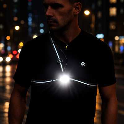 listing-lifestyle A man wearing a black Proviz reflective chest light vest at night on a city street, with the bright light turned on at the center of the chest.