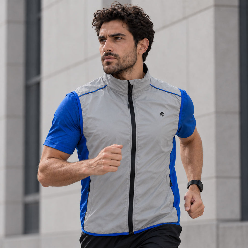 lifestyle A man running outdoors wearing a Proviz light gray reflective and blue athletic zip-up vest over a blue shirt, with a modern stone building in the background.